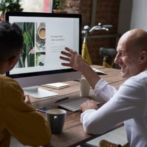 Two professionals collaborating in a modern workspace, discussing a project on a computer screen.