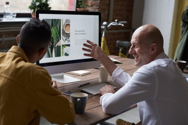 Two professionals collaborating in a modern workspace, discussing a project on a computer screen.